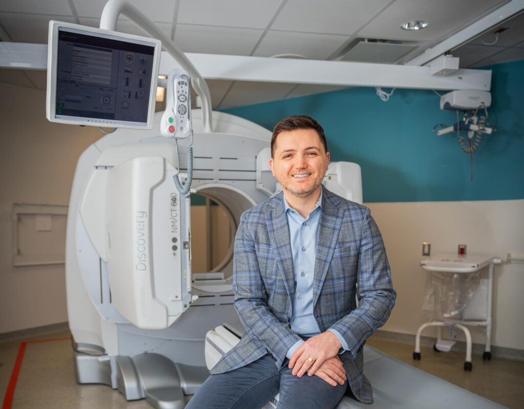 Dr. Alex Bilbily sitting in front of a CT scanner.